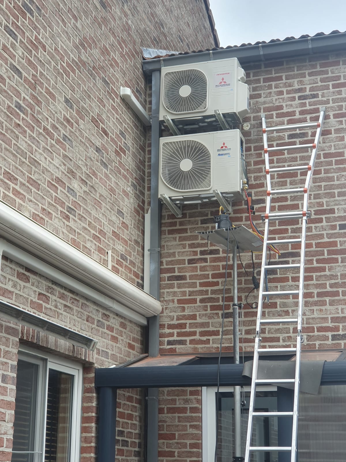 Twee buitenunits boven elkaar tegen een gevel